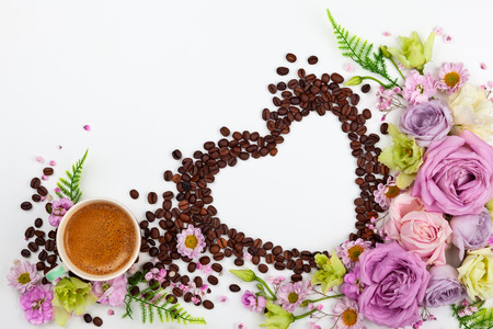 Festive concept for Valentine day or Mother's day with flowers, cup of coffee and coffee beans in shape of heart on whiteの写真素材