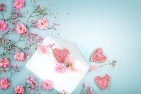 Spring floral composition made of fresh pink flowers, envelope and hearts on light pastelの写真素材
