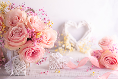 Beautiful pink roses in basket on vintage wooden table. Shabby chic style. Flower composition for holiday with copy space.の写真素材