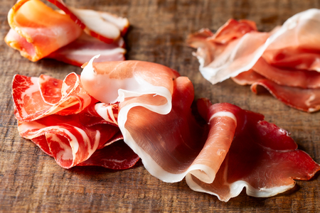 Assort of sliced jamon, salami, ham  on woodenの写真素材