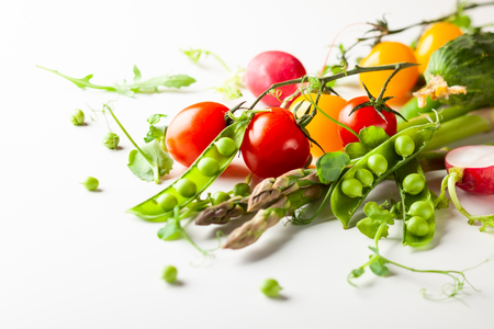 Fresh green  peas pods with sprouts, radish, tomatoes and green asparagus on white woodenの写真素材