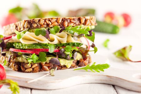 Fresh vegetarian  sandwich  with creamy avocado, cheese and fresh veggies the wooden board. Concept healthy eating. Vegetarian sandwich.の写真素材