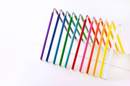 Colour pencils set on light  background with copy-space.   Pencils are reflected in the mirror...