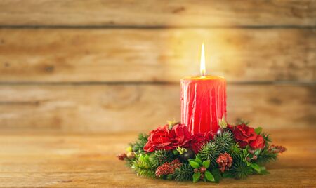 Burning Christmas red candle and  festive Christmas arrangement on a wooden table. Christmas adventの写真素材
