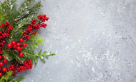 Christmas or winter background with green and frosted evergreen branches and red berries on a grey vintage board. Flat lay, winter concept with copy space.の写真素材