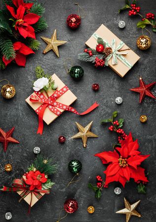 Christmas gifts, decorations and poinsettia flowers on black background. Creative winter holiday concept. Flat lay.の写真素材