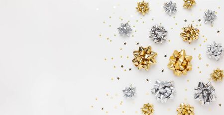 Christmas or New Year composition with gold and silver sparkling ribbon decorations on white
