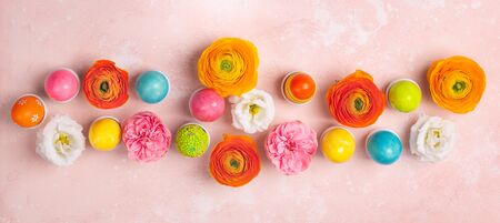 Easter eggs and colorful spring flowers on pastel pink background. Minimal holiday concept with copy...
