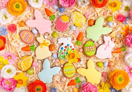 Easter cookies, eggs, Bunny, candy and colorful spring flowers on pastel  background. Creative holiday concept. Flat lay pattern.の写真素材