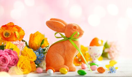Easter decoration with Easter eggs, colorful rabbits and spring flowers on white wooden table. Easter concept with copy space.の写真素材