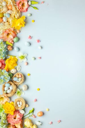 Happy Easter concept with easter eggs in nest and spring flowers. Easter background with copy space. Flat lay.の写真素材