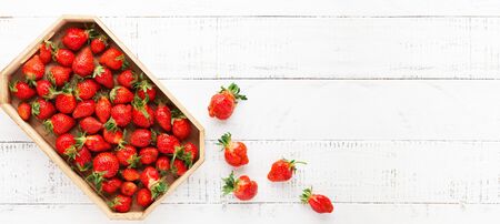 Delicious fresh strawberries in box on white wooden background. Flat lay, copy space.Ugly organic strawberriesの写真素材