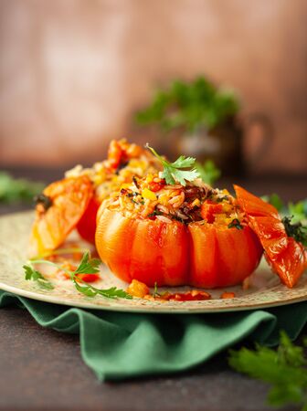 Delicious stuffed tomatoes in shape of pumpkin with rice, vegetables and meat. Concept homemade healthy eating.の写真素材