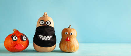 Funny pumpkins with faces and in a black protective mask on pastel blue background. Concept celebration of Halloween or Thanksgiving in the conditions of coronavirus.の写真素材