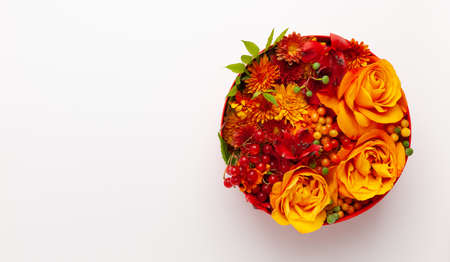 Festive composition with beautiful flowers and berries in red round box on white background. Flat lay, copy space.の写真素材