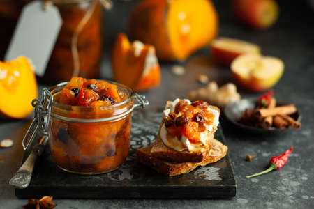 Homemade pumpkin and apple chutney with raisins in jars and on toast bread. Delicious sweet spicy sauce preserved for autumn and winter season.の写真素材