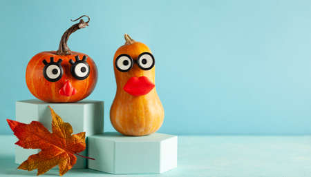Funny pumpkins with faces on pastel blue background with copy space. Concept celebration of Halloween or Thanksgiving.の写真素材