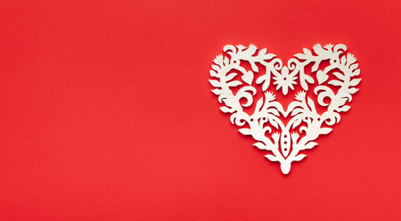 Festive composition with openwork white heart on redの写真素材