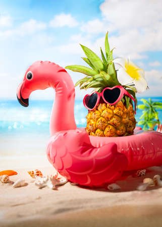 Pink inflatable flamingo and hipster pineapple in sunglasses. Summer pool float party idea. Summer creative concept.の写真素材