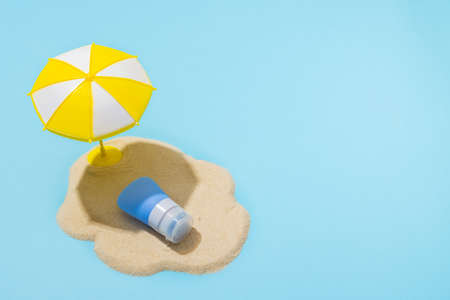 Sunscreen cream on sand and sun umbrella