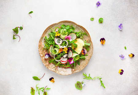Delicious summer salad with edible flowers, vegetables, fruit, microgreens and cheese. Clean and healthy eating concept. Top view.の写真素材