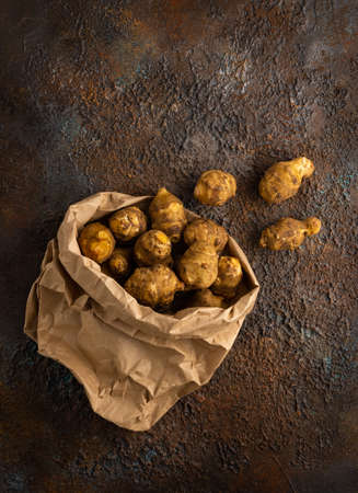 Organic Jerusalem artichoke in paper package on textured background. Autumn harvest of root...