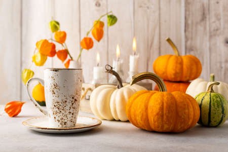 Autumn still life with cup of tea, pumpkins, flowers and candles on table. Thanksgiving day or halloween concept.の写真素材