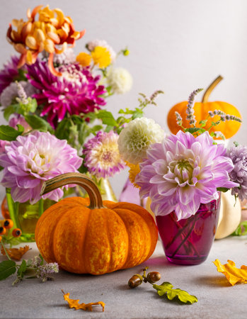 Autumn still life with bouquet of flowers and white and orange pumpkins on table. Autumn decoration for home.の写真素材