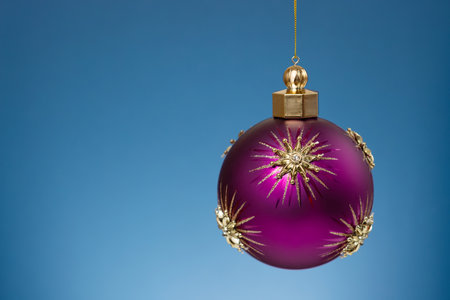 Christmas purple ball with gold stars on festive blue background. Christmas ornaments and New Year decor.の写真素材