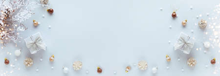 Christmas or New Year concept with gift box, festive baubles and snowy branch with pine cones on pastel background. Flat lay, copy spaceの写真素材
