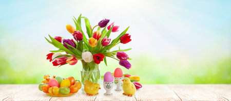 Easter still life with Easter eggs, bouquet of colorful tulips and chicks on wooden table. Happy...