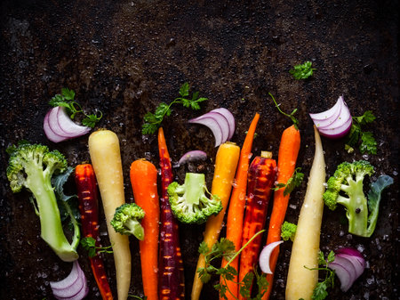 raw rainbow carrot, broccoli and onion for roasting, on a baking trayの写真素材