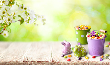 A cheerful spring setup featuring candy-filled pastel buckets, ceramic bunny figurines with polka...