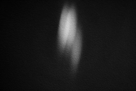 Abstract monochrome image featuring a light reflection that forms a soft, blurred shape on a...