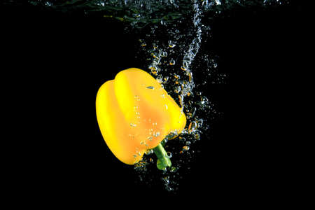Yellow pepper and bright water splash. Healthy and tasty food on black background.の写真素材