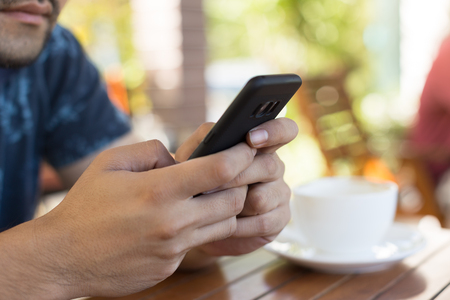 Closeup of people hand using smart phone at coffee shopの写真素材