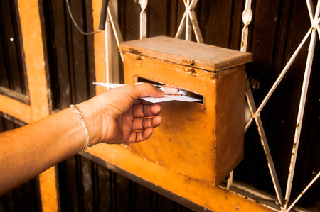 closeup on a female hand putting a letter in a letterbox
