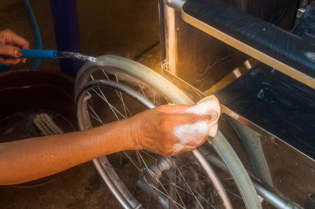 woman cleaning old wheelchair by sponge,asian washing styleの写真素材