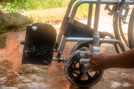 woman cleaning old wheelchair by sponge,asian washing styleの写真素材