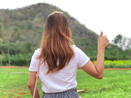 Torist girls showing the tumb up with nature view,green tree and mountain with sky