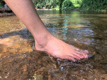 Woman leg in the water at waterfall,relax time with nature