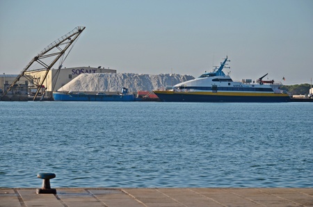 transport ship and mountain of salt in the port of Trapani city in Sicily, Italyの写真素材