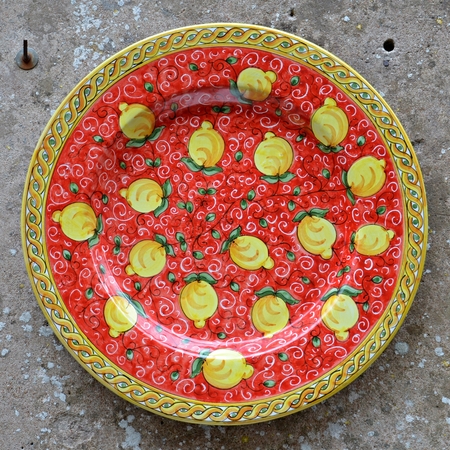 close up of typical colorful sicilian pottery - red ceramic plate with yellow lemonsの写真素材