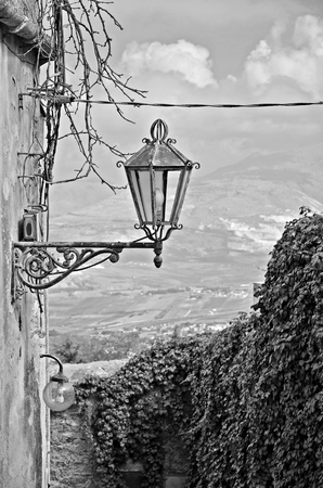 Old Sicilian alley with lamp and hedge in black and white.の写真素材