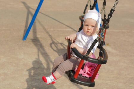 Adorable girl having fun on a swing on summer dayの写真素材