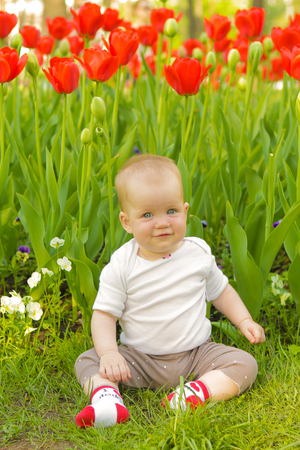 young adorable cheerful baby sit in park on green grass and playingの写真素材