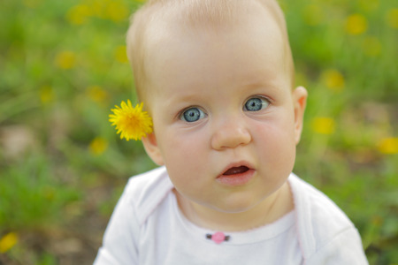 young adorable cheerful baby sit in park on green grass and playingの写真素材