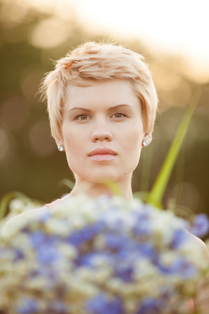 Portrait of a smiling young woman with flowers in parkの写真素材
