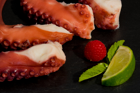 Cooked Octopus Plate with lime in black stone background. Close upの写真素材