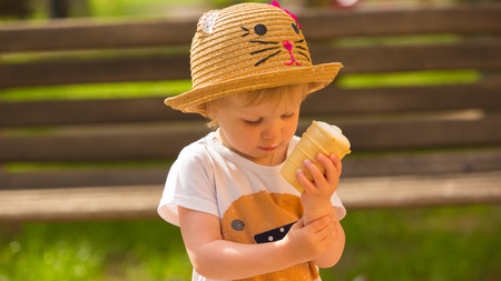 Cute Toddler Girl Eating Ice-Cream at park at backgroundの写真素材